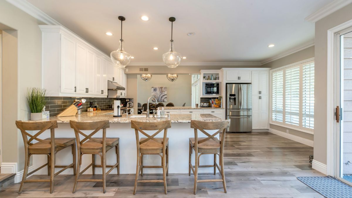 A modern kitchen featuring white cabinets and warm wooden floors, creating a bright and inviting atmosphere.