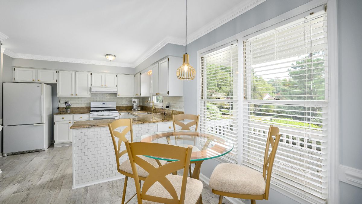 A cozy kitchen featuring a wooden table surrounded by chairs, creating a welcoming dining space.