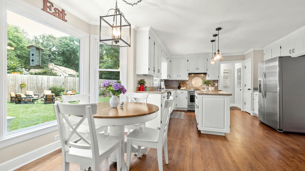 A modern kitchen featuring white cabinets and elegant hardwood floors, creating a bright and inviting atmosphere.